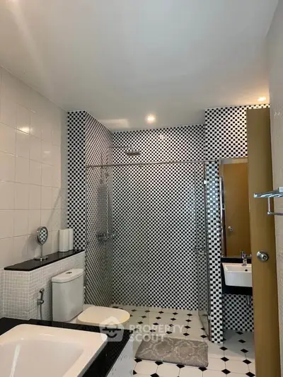 Modern bathroom with stylish black and white checkered tiles and sleek fixtures.