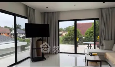 Spacious living room with large windows and balcony access, offering a serene view of the neighborhood.