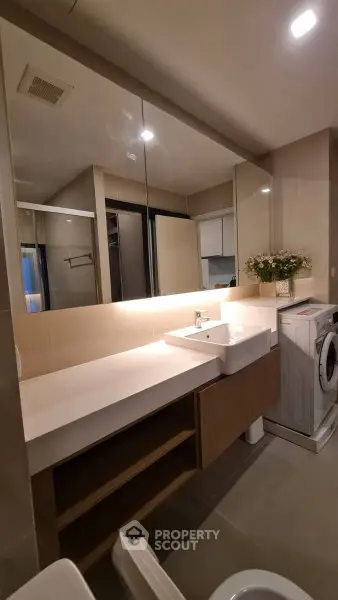 Modern bathroom with sleek vanity and washing machine in stylish apartment.