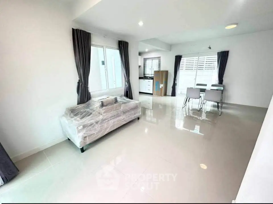 Spacious modern living room with dining area and large windows in a bright apartment.