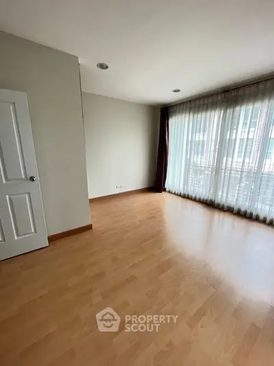 Spacious empty room with large windows and wooden flooring, perfect for customization.