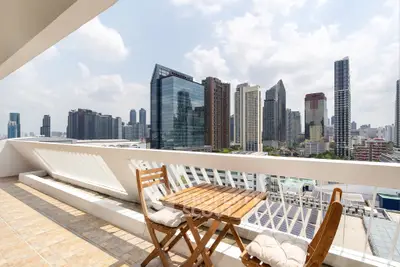 Stunning cityscape view from a spacious balcony with cozy seating, perfect for relaxation and enjoying urban living.