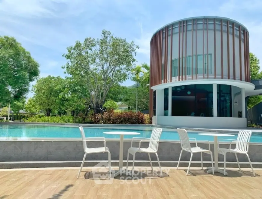 Luxurious modern villa with poolside seating and lush greenery, perfect for relaxation and entertainment.