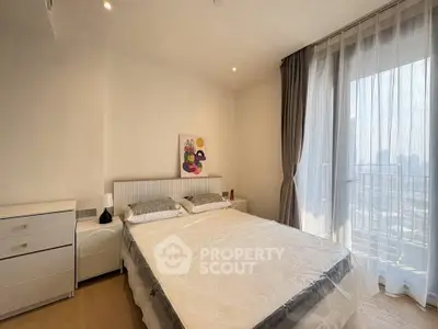 Bright and airy bedroom with large window and modern decor in a high-rise apartment.