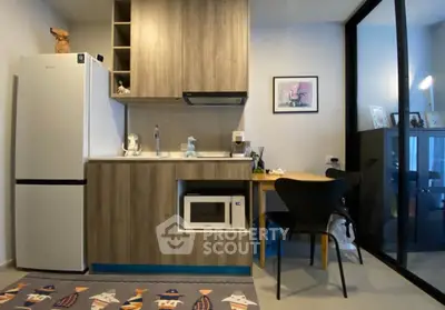 Modern compact kitchen with wooden cabinets, microwave, and fridge in cozy apartment.