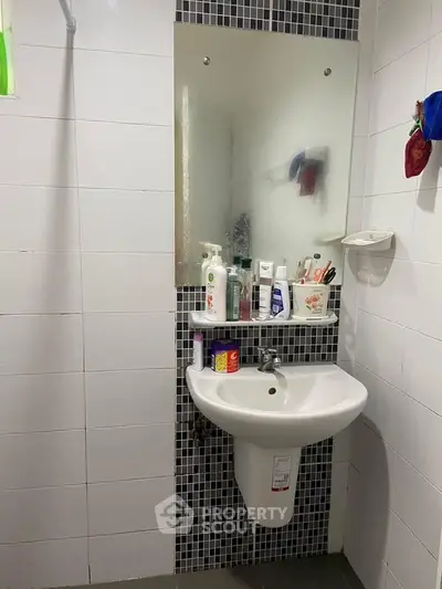 Modern bathroom with sleek sink and mirror, featuring stylish tile accents and organized toiletries.