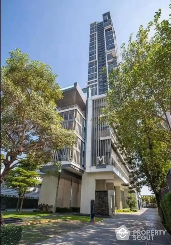 Modern high-rise building with lush greenery and clear blue sky