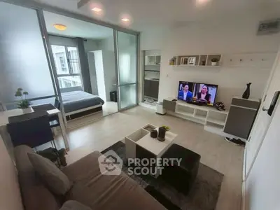 Modern open-plan living room with stylish decor and a view into the bedroom