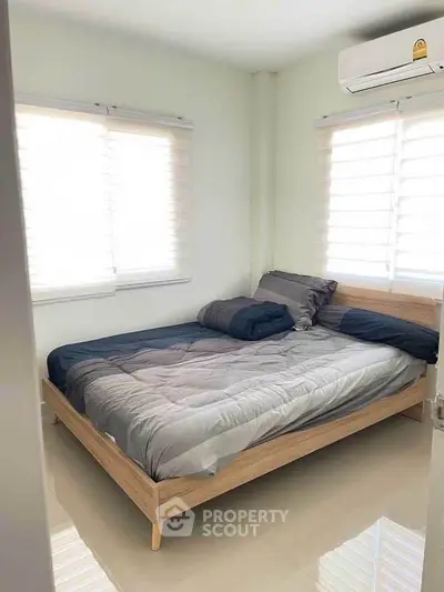 Cozy bedroom with modern bed and natural light from large windows, perfect for relaxation.