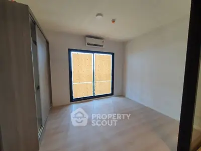 Spacious empty bedroom with large window and air conditioning unit.