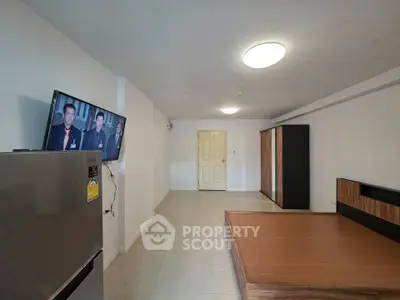 Spacious minimalist bedroom with modern furnishings and wall-mounted TV