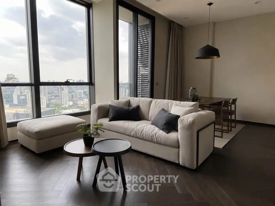 Modern living room with large windows offering stunning city views, featuring elegant furniture and stylish decor.