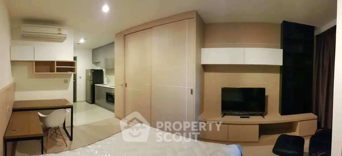 Modern studio apartment with sleek built-in furniture and compact kitchen area.
