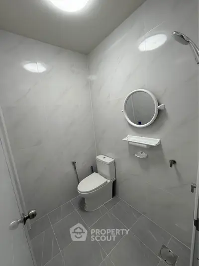Modern minimalist bathroom with sleek white tiles and round mirror