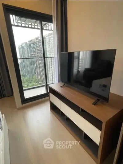 Modern living room with TV and balcony view in high-rise apartment