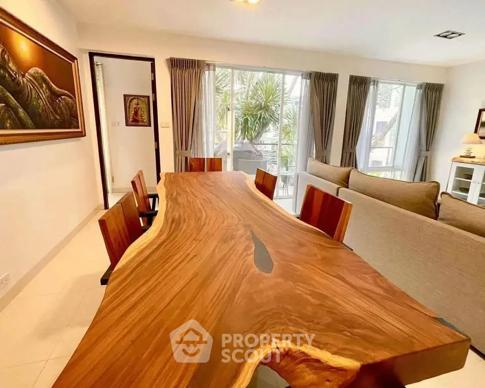 Stunning open-plan living room with unique wooden dining table and large windows offering natural light.
