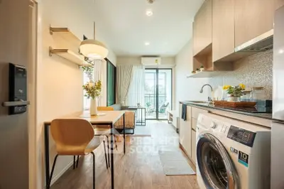 Modern kitchen with open layout and washing machine, featuring stylish dining area and bright natural light.