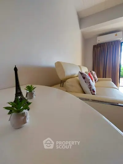 Modern living room with elegant white furniture and decorative accents, featuring a cozy ambiance.