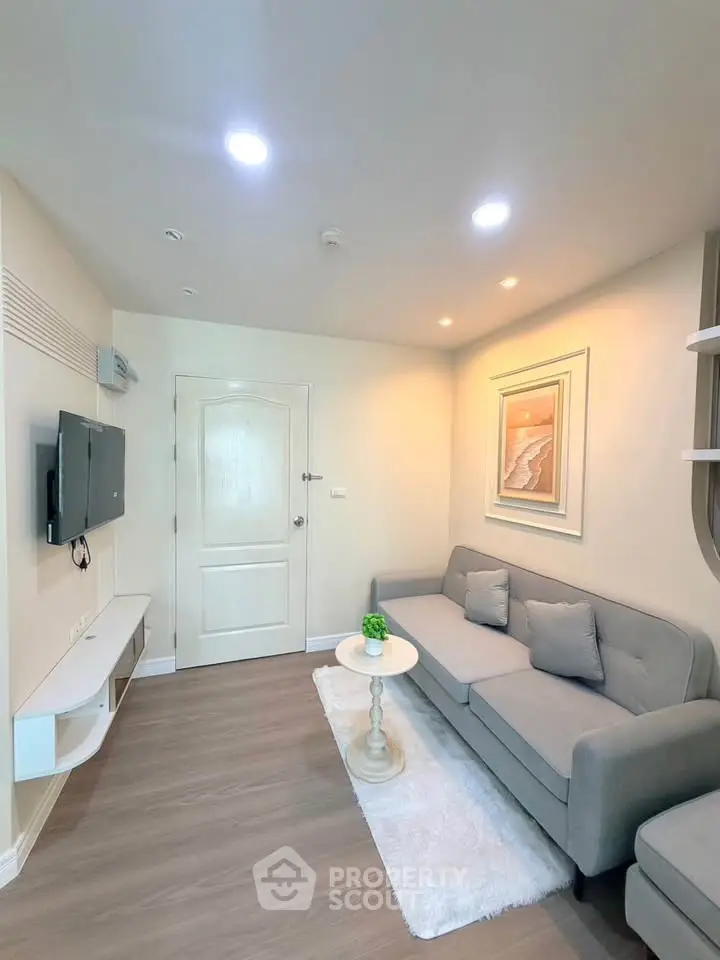 Cozy living room with modern gray sofa, wall-mounted TV, and stylish decor in a bright apartment.
