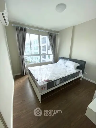 Modern bedroom with large window and natural light in a stylish apartment.