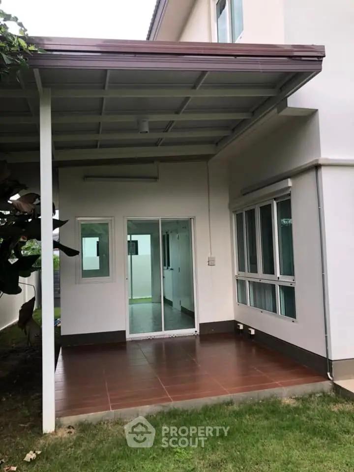 Charming covered patio with sliding glass doors and lush green lawn, perfect for outdoor relaxation.