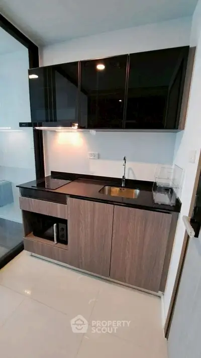 Modern compact kitchen with sleek black cabinets and built-in appliances