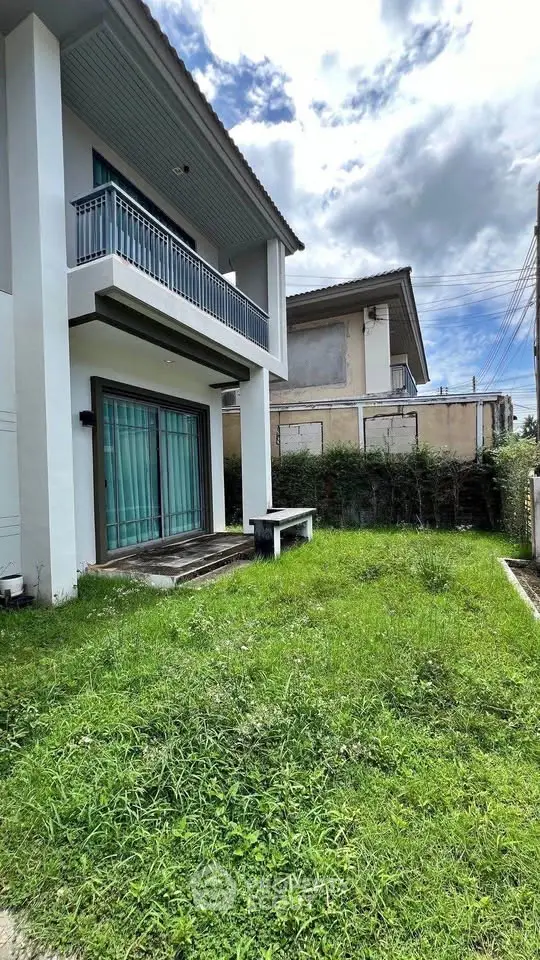Modern two-story house with lush green garden and balcony