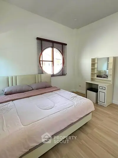 Spacious bedroom with modern furnishings and natural light, featuring a cozy bed and stylish vanity.