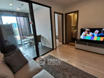 Modern living room with balcony and TV, featuring sleek design and natural light.