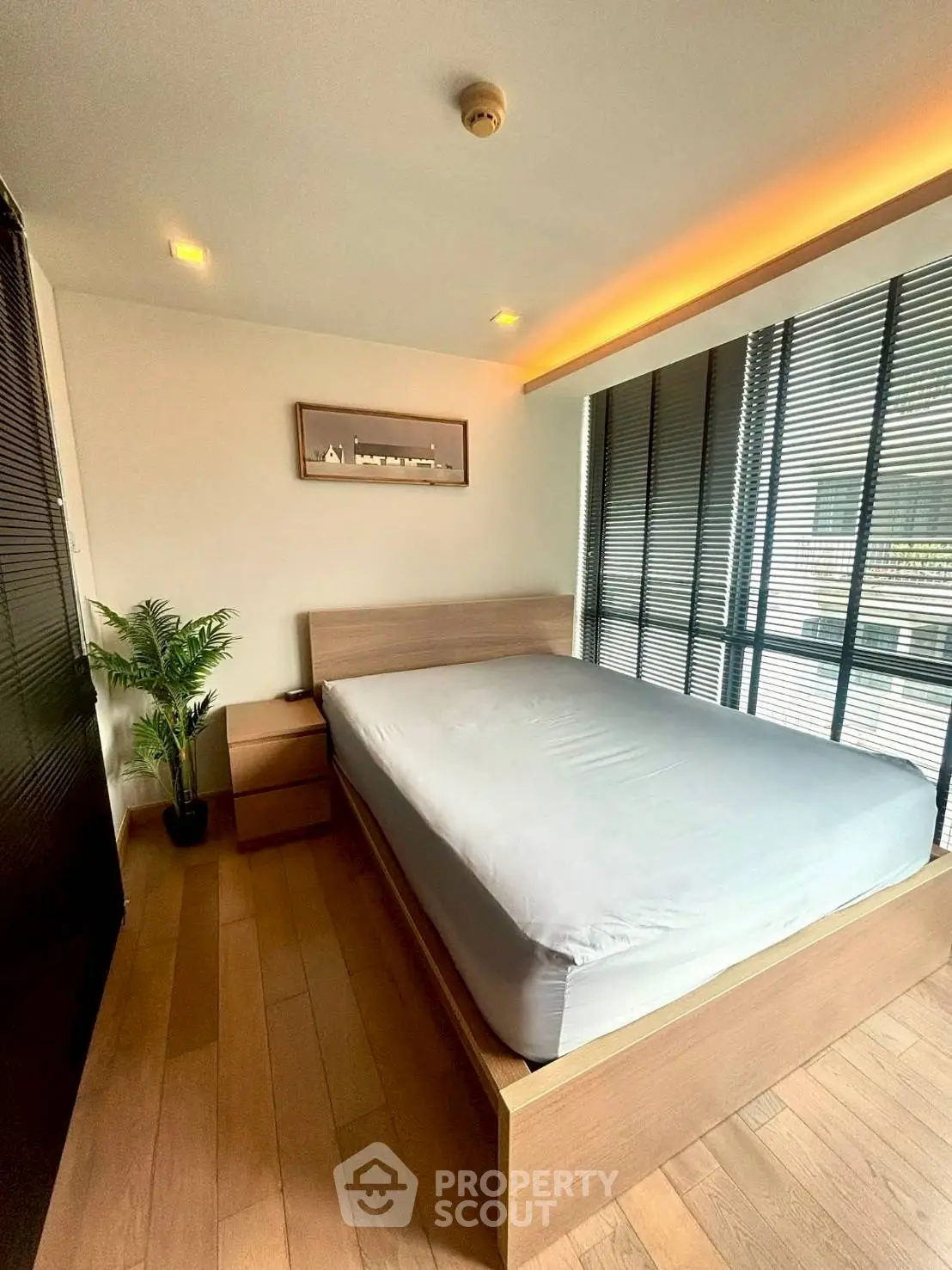 Modern bedroom with large windows and wooden flooring in a stylish apartment.
