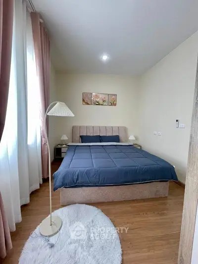 Cozy bedroom with elegant decor and natural light, featuring a plush bed and stylish lighting.
