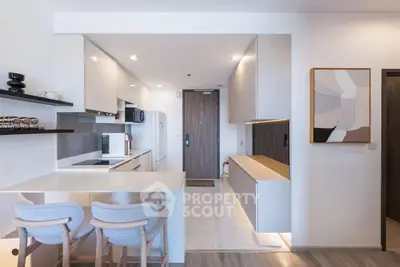 Modern kitchen with sleek design and open layout, featuring stylish bar stools and contemporary artwork.