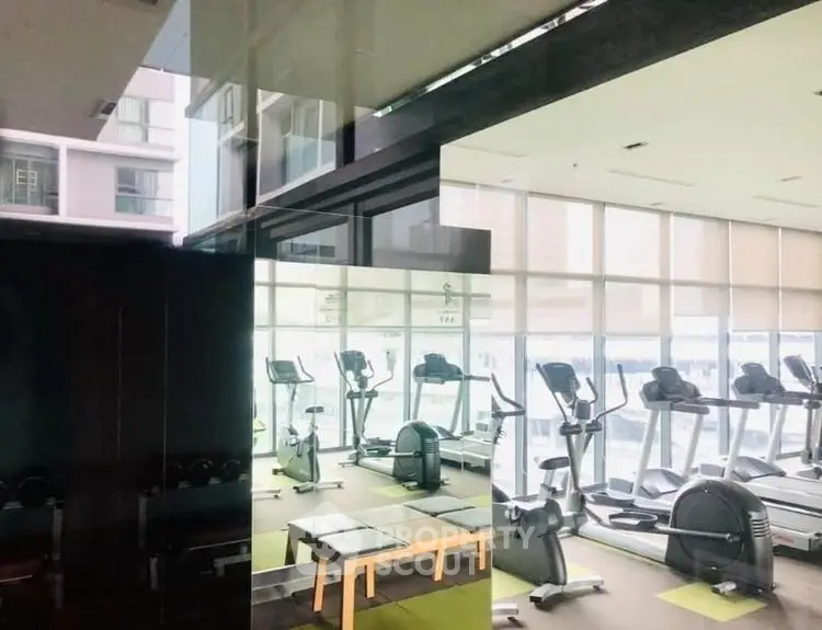 Modern gym with large windows and exercise equipment in a high-rise building.