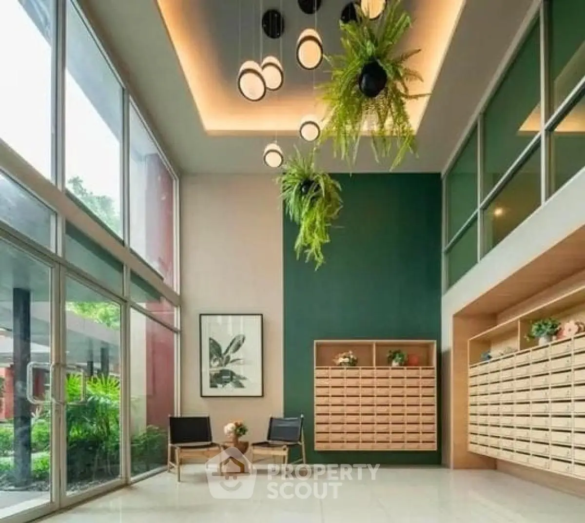 Modern building lobby with stylish lighting and greenery, featuring mailboxes and seating area.