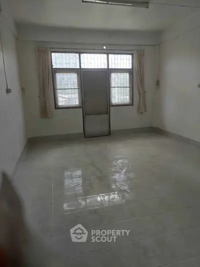 Spacious empty room with large window and tiled floor, ideal for customization.