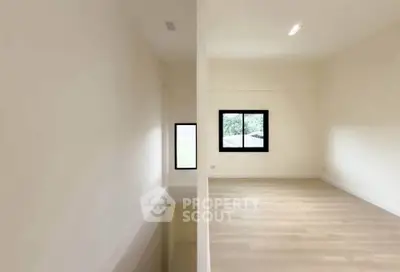 Spacious minimalist room with large windows and wooden flooring, perfect for modern living.