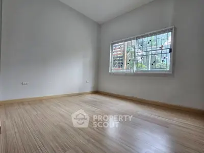Spacious empty room with large window and wooden flooring, perfect for customization.