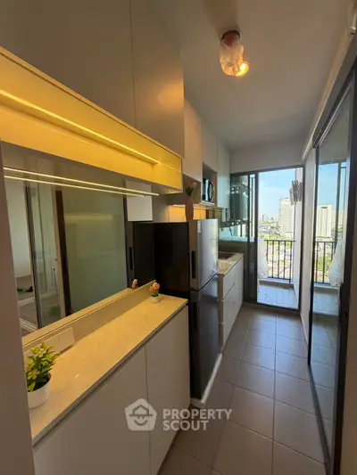 Modern kitchen with sleek design and city view from balcony, featuring built-in appliances and ample storage.
