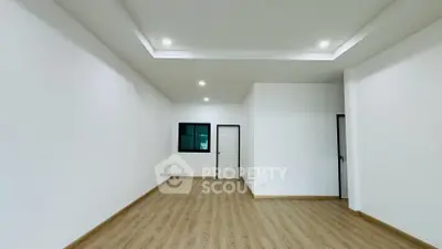 Spacious empty room with wooden flooring and recessed lighting, perfect for customization.