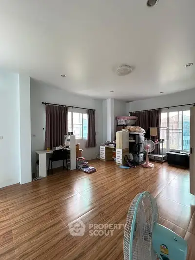 Spacious living room with wooden flooring and large windows for natural light.