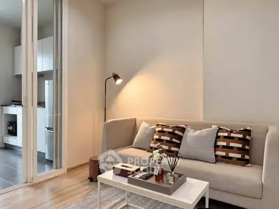 Modern living room with cozy sofa and stylish decor adjacent to a sleek kitchen area.