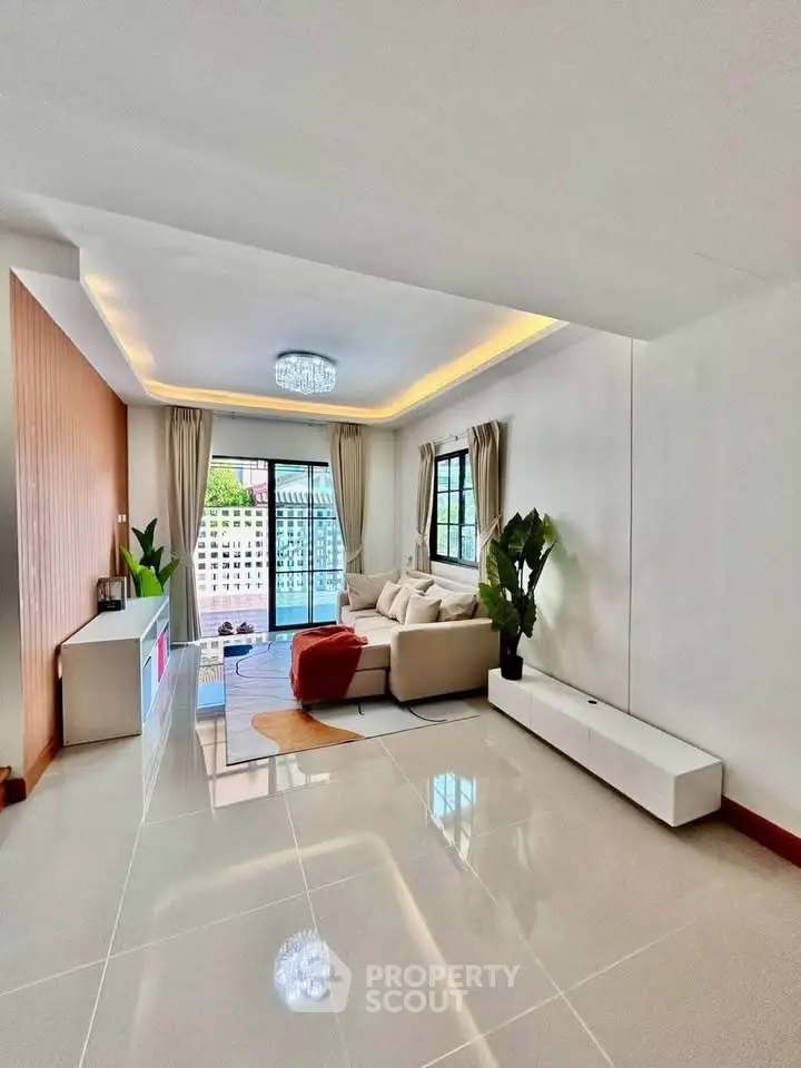 Spacious modern living room with elegant decor and large windows opening to a balcony.