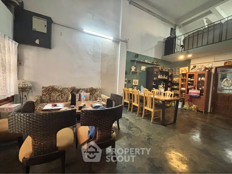 Spacious living and dining area with eclectic decor and high ceilings.