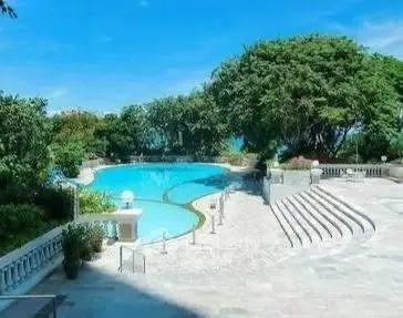 Luxurious outdoor pool area with lush greenery and elegant stone steps, perfect for relaxation.