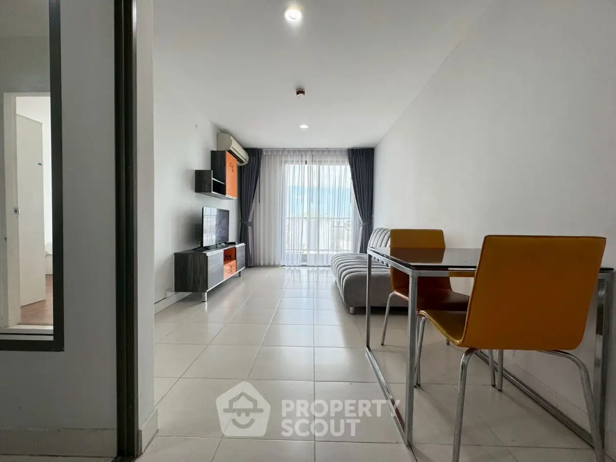 Modern living room with sleek furniture and natural light from large window.