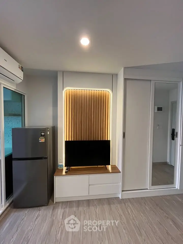 Modern living room with sleek TV unit and refrigerator, featuring stylish wood paneling and ambient lighting.