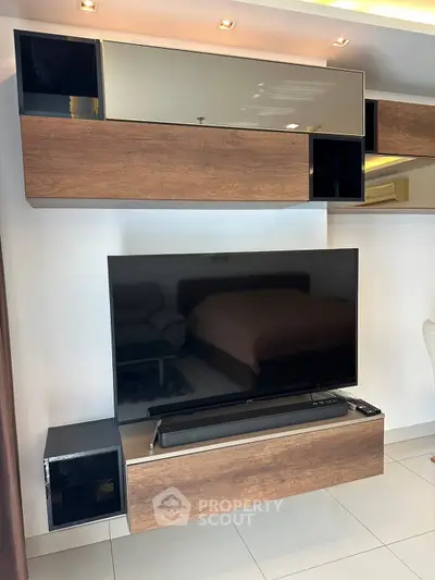 Modern living room with sleek TV setup and stylish wooden cabinets.