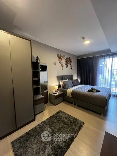 Modern bedroom with stylish decor and ample natural light, featuring a cozy bed and sleek furniture.
