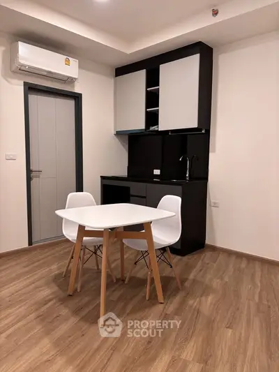 Modern kitchen with sleek cabinetry and cozy dining area in a stylish apartment.