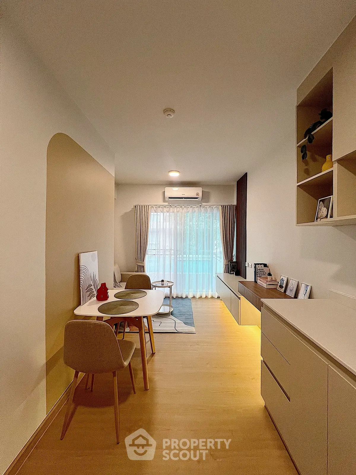 Modern living room with elegant decor and natural light, featuring a cozy dining area and stylish shelving.
